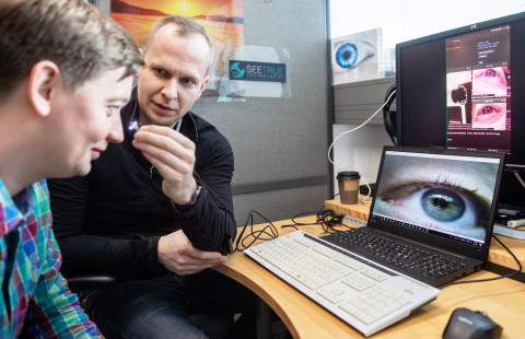 Two men sitting in front of computer screens showing eye-tracking technology.