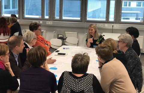 Ihmisiä istumassa pöydän ympärillä tekemässä ryhmätyötä.