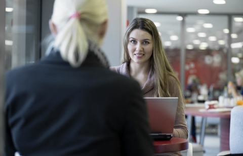 Nainen istuu kahvilassa tietokoneen kanssa