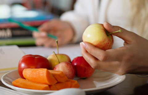 Tyttö pitelee omenaa kädessään.