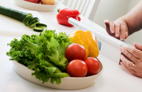 Nainen lukee tablet-tietokonetta. Vihanneksia astiassa.