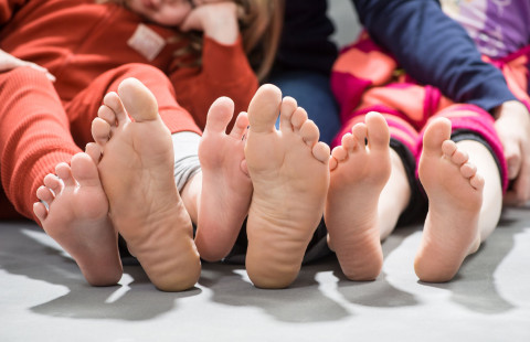 perhe istuu lattialla paljaat jalkapohjat näkyvillä