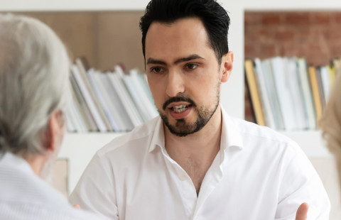 Mies keskustelee ikääntyneen pariskunnan kanssa.