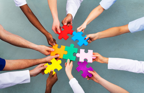 Värikkäitä palapelinpaloja käsissä.