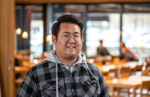 Young man smiling at the camera, cafeteria on the background.