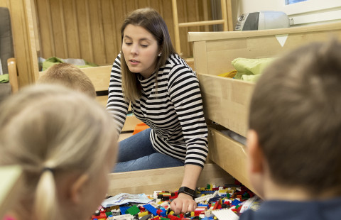 lapset ja opettaja leikkivät legoilla päiväkodissa
