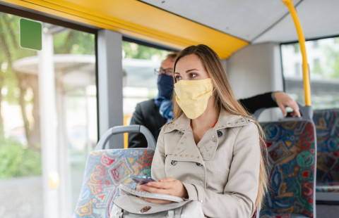 Ihmisiä bussissa maski kasvoillaan