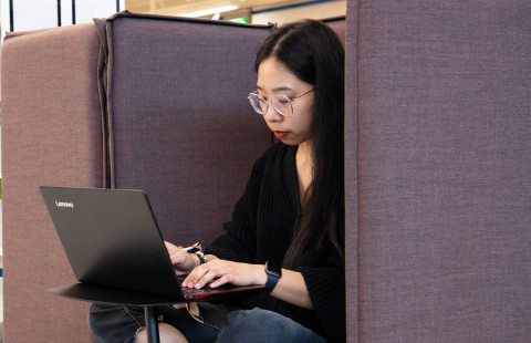 Nuori nainen työskentelee tietokoneella UEFin kirjastossa.