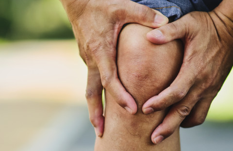 Man holding an aching knee.