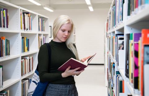 Naispuolinen opiskelija lukee kirjaa UEFin kirjastossa.