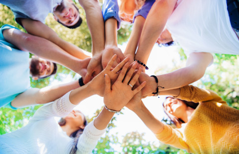 Ryhmä ihmisiä pitää käsiä päällekkäin.