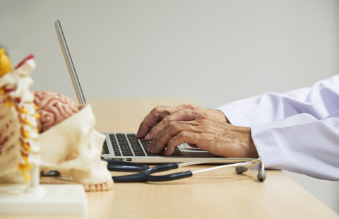 Lääkäri kannettavan tietokoneen ääressä