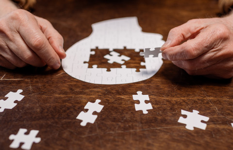 Kädet kokoamassa palapeliä.