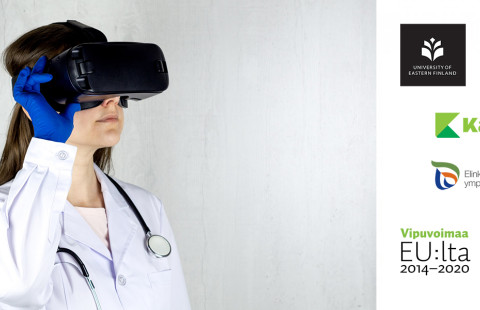 Labratakkinen henkilö, jolla vr-lasit kasvoilla, suojahansikas kädessä, stetoskooppi kaulalla.