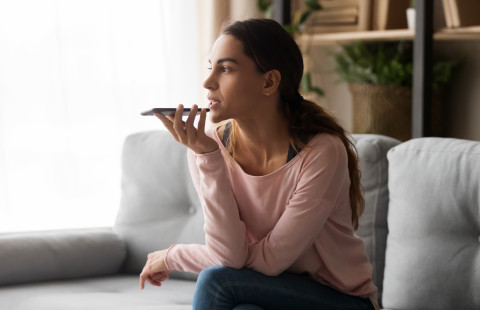 Nainen käyttää matkapuhelimen puheentunnistusta.