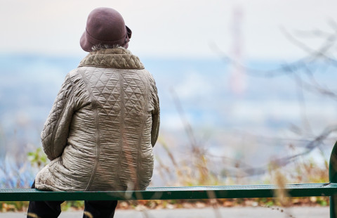 Vanha nainen istuu puistonpenkillä.