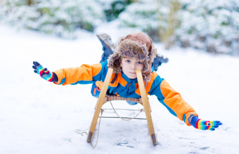 Lapsi laskee mäkeä kelkalla