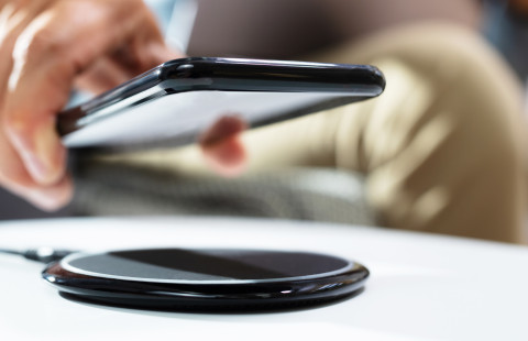 Man charging smartphone using wireless charging pad.