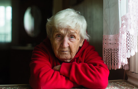 Ikääntynyt nainen istuu pöydän ääressä