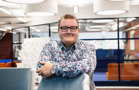 Young man with glasses standing and looking at the camera.