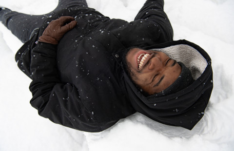 Man lying in snow and laughing