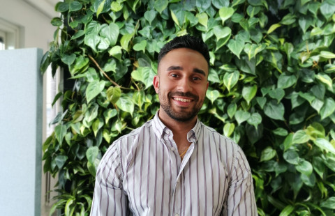 Opiskelija hymyilee kameralle takanaan vihertävä tausta.