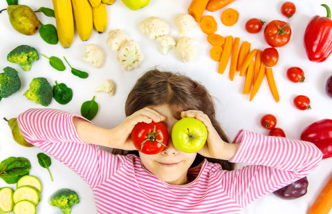 Lapsi kasviksia käsissä.