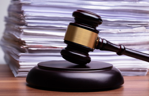 Judge gavel in front of stacked files on table.