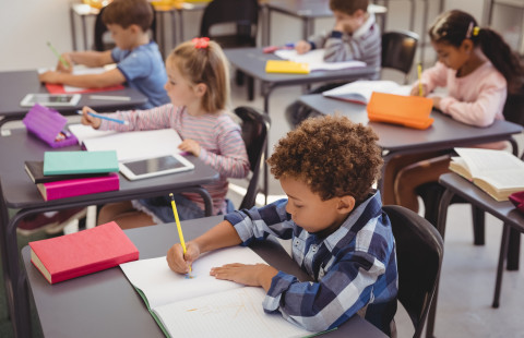 Oppilaita luokkahuoneessa pulpettien ääressä.