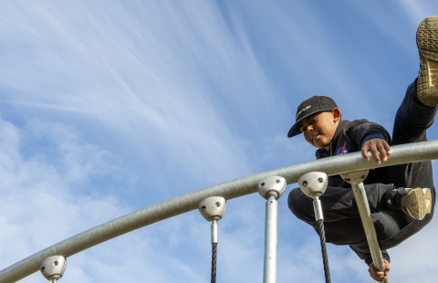 Kiipeilevä poika koulun pihalla.