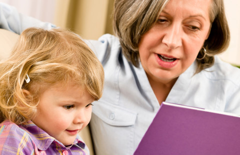 Lapsenlapsi ja isoäiti lukemassa.