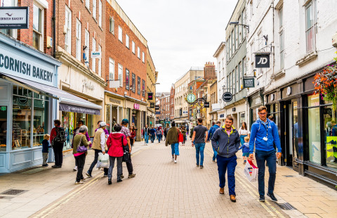 Ihmisiä kävelemässä kapealla talojen ympäröimällä kadulla.