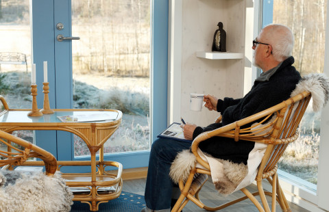 Old man sitting and looking out of a window.
