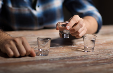 Hand holding a vodka shot.