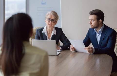 Kolme ihmistä palaverissa pöydän ääressä.