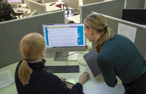 Two library customers looking at an article on a computer screen