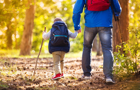 Father and son walking in autumn forest.
