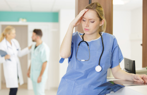 Nurse holding her forehead.
