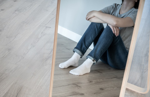 Henkilö istuu lattialla.