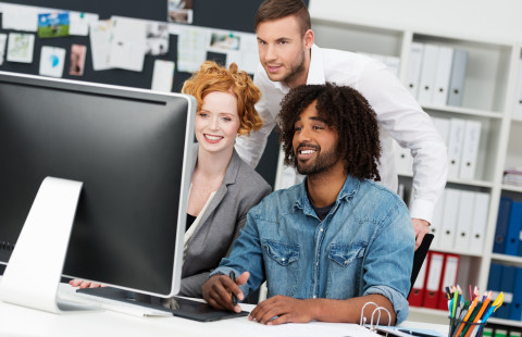 Kolme henkilöä näyttöpäätteellä.