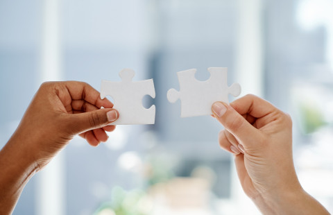 Hands keeping pieces of puzzle.