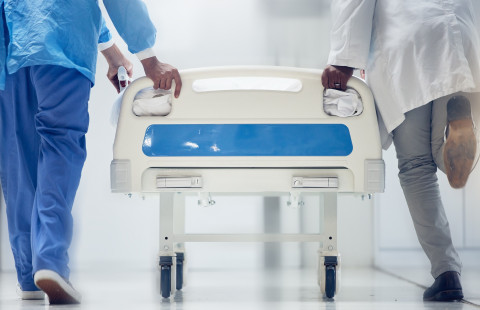 Kaksi sairaanhoitajaa kuljettaa sairaalasänkyä.