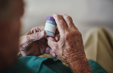 Lääkepurkki vanhuksen käsissä.