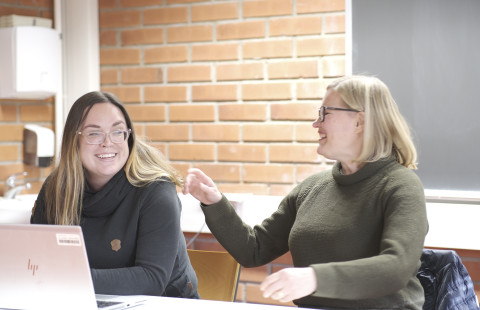 Kaksi naista keskustelevat seminaarisalissa innostuneesti.