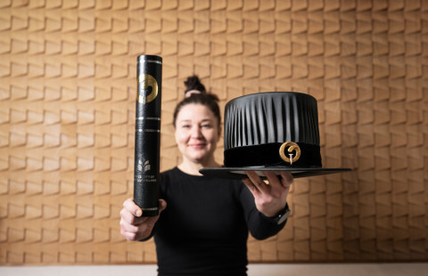 Elisa Sulkinoja pitelee Diplomikoteloa ja tohtorinhattua.