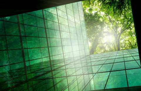 Alhaaltapäin kuvattu lasiseinäinen rakennus, puita pilkistää ylhäältä.