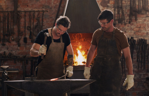 Miehet takovat alasimella hehkuvaa rautaa.