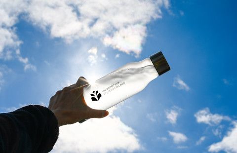 UEF-juomapullo vasten kesäistä taivasta.