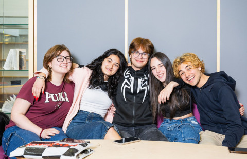 Ryhmä oppilaita hymyilee kameralle pöydän takana.