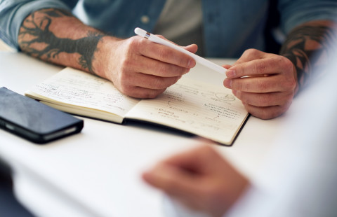 Kädet muistikirjan päällä.